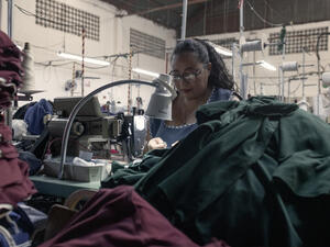 A woman in a factory works at a sewing machine.
