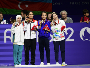 Quatre femmes se tiennent côte à côte en brandissant des médailles autour de leur cou.
