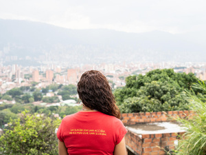 A woman pictured from behind, looking out across downtown Medellín, Colombia