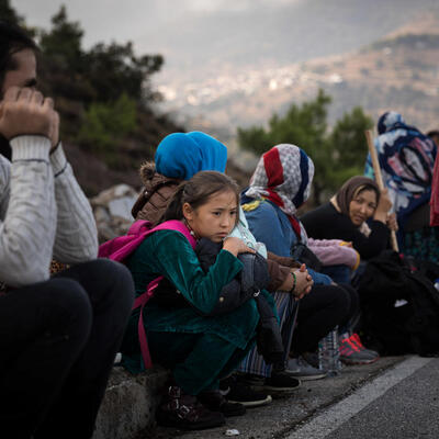 Des hommes, des femmes et des enfants attendent sur le bord de la route en Grèce.