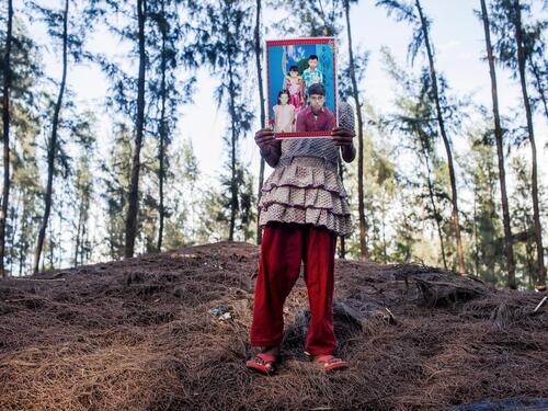 A young girl holds in front of her a photo of her lost 15-year-old brother.