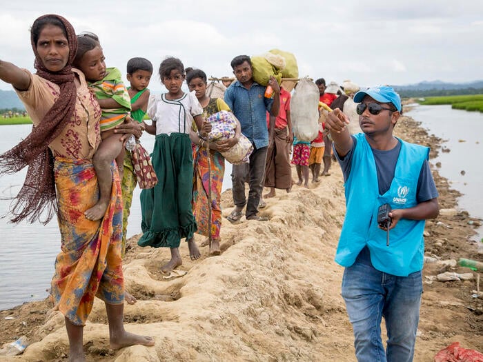 A UNHCR staff member shows a group of Rohingya refugees the direction to a transit centre.