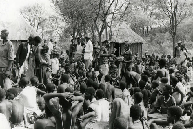 Black and white photo of a group of Angolan refugees waiting for food rations