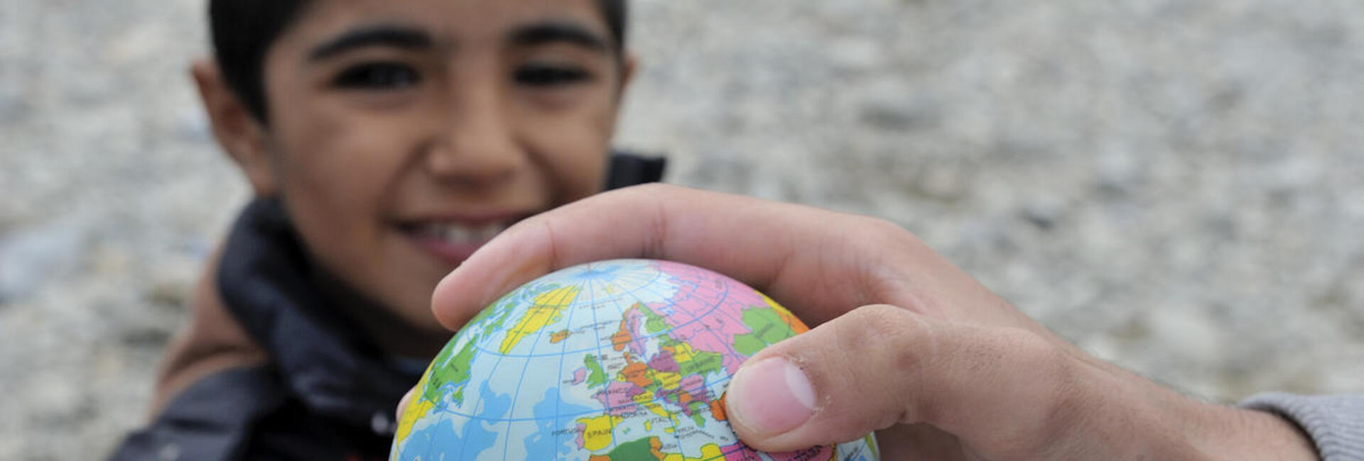 Un jeune garçon tient une petite mappemonde.