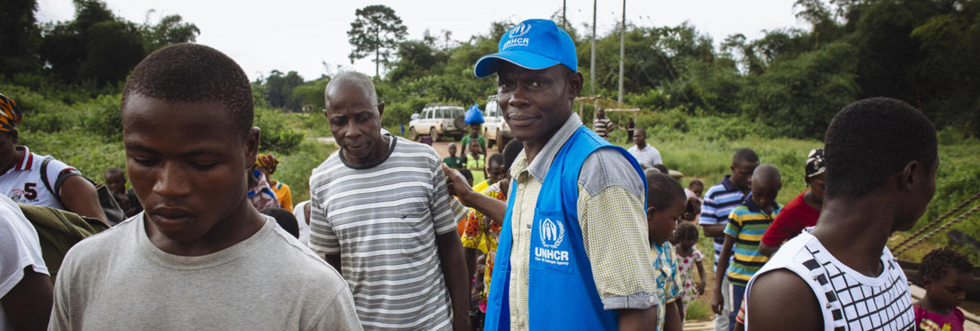 A UNHCR staff member helps refugees board a ferry that will take them home to Côte d'Ivoire.