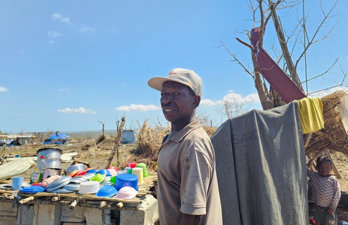 Un homme coiffé d'une casquette de base-ball observe les dégâts causés par un cyclone.