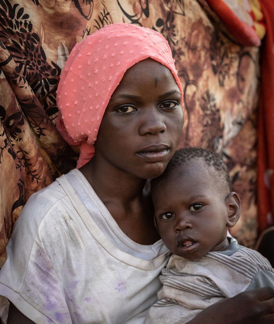 A young woman from South Sudan holds her one-year-old sister.