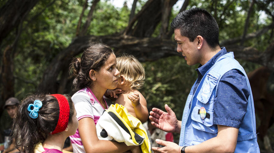 Une femme avec deux jeunes enfants échange avec un employé du HCR, en Colombie.