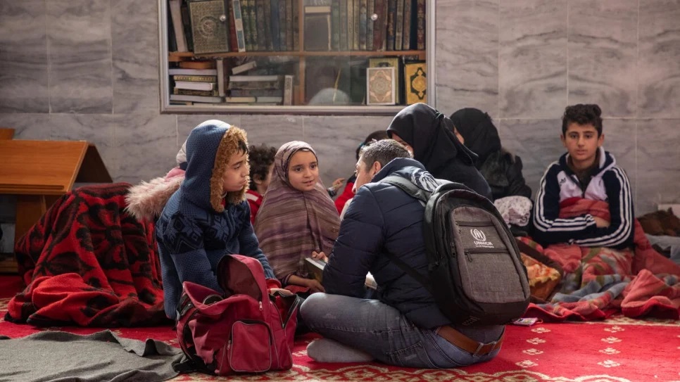A UNHCR staff member speaks to a boy and his family staying at the mosque in Aleppo_UNHCR_Hameed Maarouf