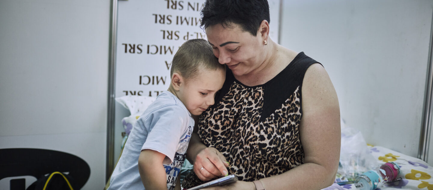 'Antonina* und ihr Sohn Artem betrachten ein Familienfoto in ihrem Zimmer in einer Flüchtlingsunterkunft in Chisinau, Moldawien. (*Antonia nahm nicht an der Absichtsumfrage teil) © UNHCR/Andrew McConnell