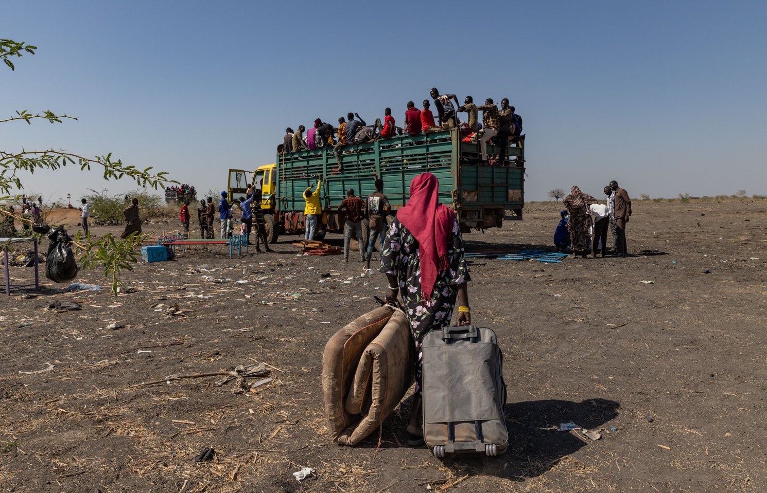 A woman carries her belongings towards a truck taking refugees and returnees from the border in South Sudan