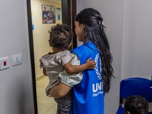 أحد موظفي قسم التسجيل في المفوضية السامية للأمم المتحدة لشؤون اللاجئين تحمل طفلاً سودانياً بعد إتمام عملية تسجيله في القاهرة.