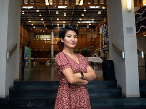A woman with folded arms stands in front of a conference venue in Geneva.