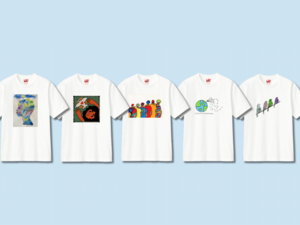 Five white t-shirts with unique artistic designs: one featuring a person painted with watercolors, another depicting a person with a dove, a third displaying a group of people, a fourth showcasing the Earth with a paper airplane, and the fifth has a design of four birds in a line.