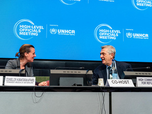 A woman and a man face each other at the podium.