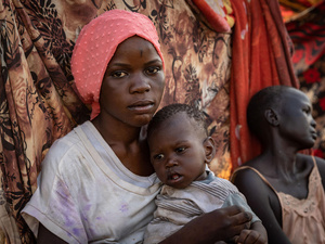 A young woman from South Sudan holds her one-year-old sister.