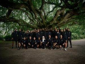 Un grand groupe de personnes posent, souriant, sous un grand arbre.