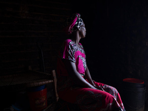 Portrait of a woman with her face turned away against a dark background.