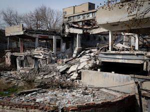An exterior view of war-damaged buildings with collapsed roofs and walls.