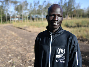 Portrait d'un homme vêtu d'un survêtement de la marque du HCR, debout sur un chemin de terre.