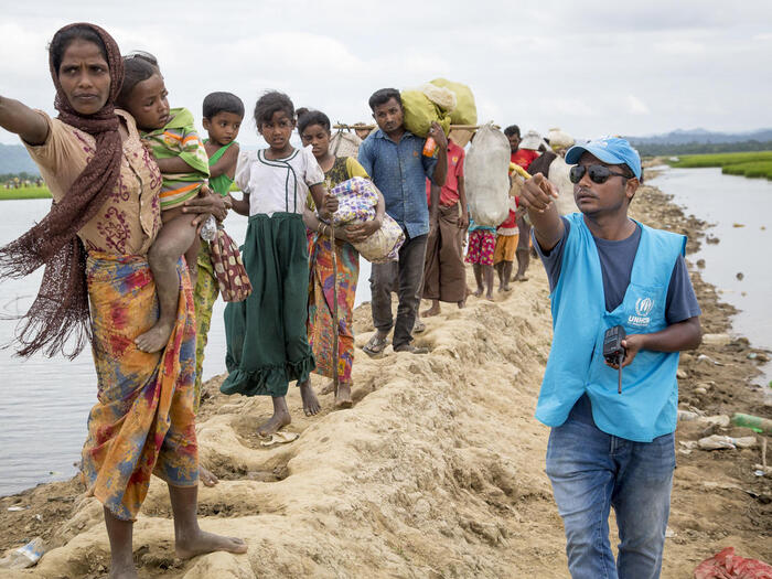 Un employé du HCR montre la direction d’un centre de transit à un groupe de réfugiés Rohingyas. 