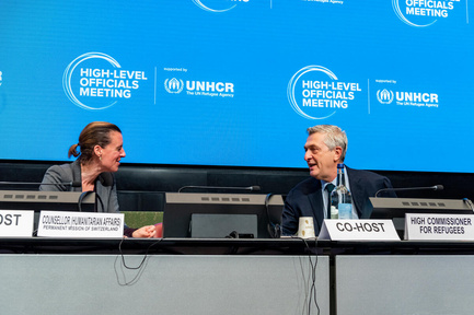 A woman and a man face each other at the podium.
