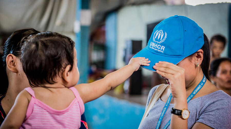 Un enfant attrape la casquette bleue d’une employée du HCR 