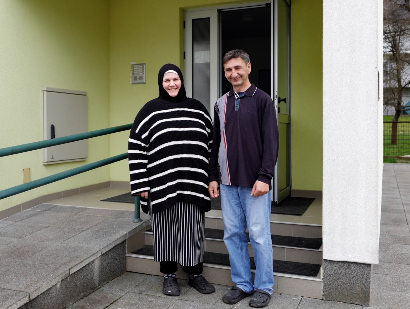 Anes, right and his wife in front of their apartment building, provided by the Regional Housing Programme in Bosnia and Herzegovina.