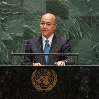 A man in a suit speaks at a podium bearing the United Nations emblem