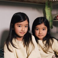 Two young girls in matching knitted sweaters.