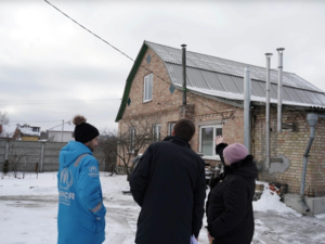 Woman shows her house to UNHCR staff that was repaired after an attack.