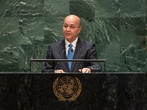 A man in a suit speaks at a podium bearing the United Nations emblem