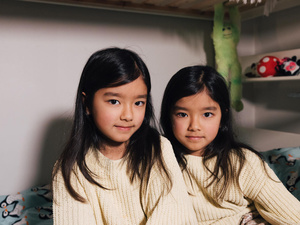Two young girls in matching knitted sweaters.