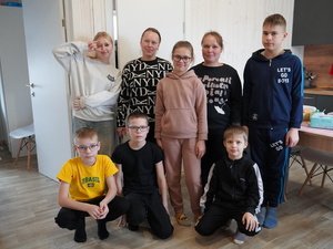 Two mothers surrounded by their six children gather for a group photo in their kitchen
