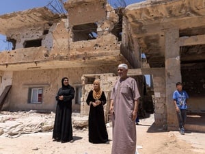 A family of four refugee returnees stand in front of a partially-collapsed building – their home in Daraa, southern Syria