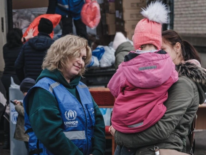 A mother holding a young child speaks with UNHCR's partner Mission Proliska's staff in Ukraine