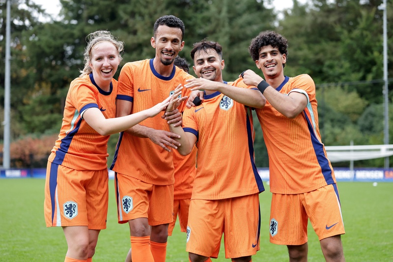 Four team members from the Netherlands celebrate on the pitch.