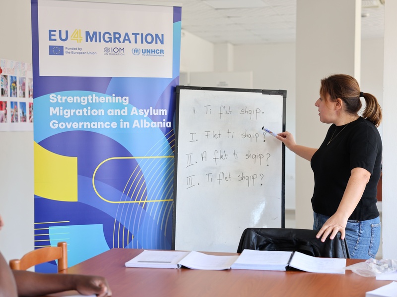  Jorida Pina, a seasoned Albanian language teacher, stands in a classroom at the National Reception Centre for Asylum in Tirana, teaching a lesson on commonly used Albanian verbs. 
