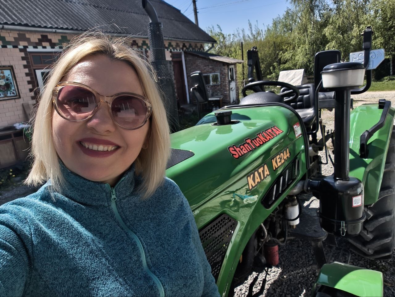 Alina stands in front of a green tractor.