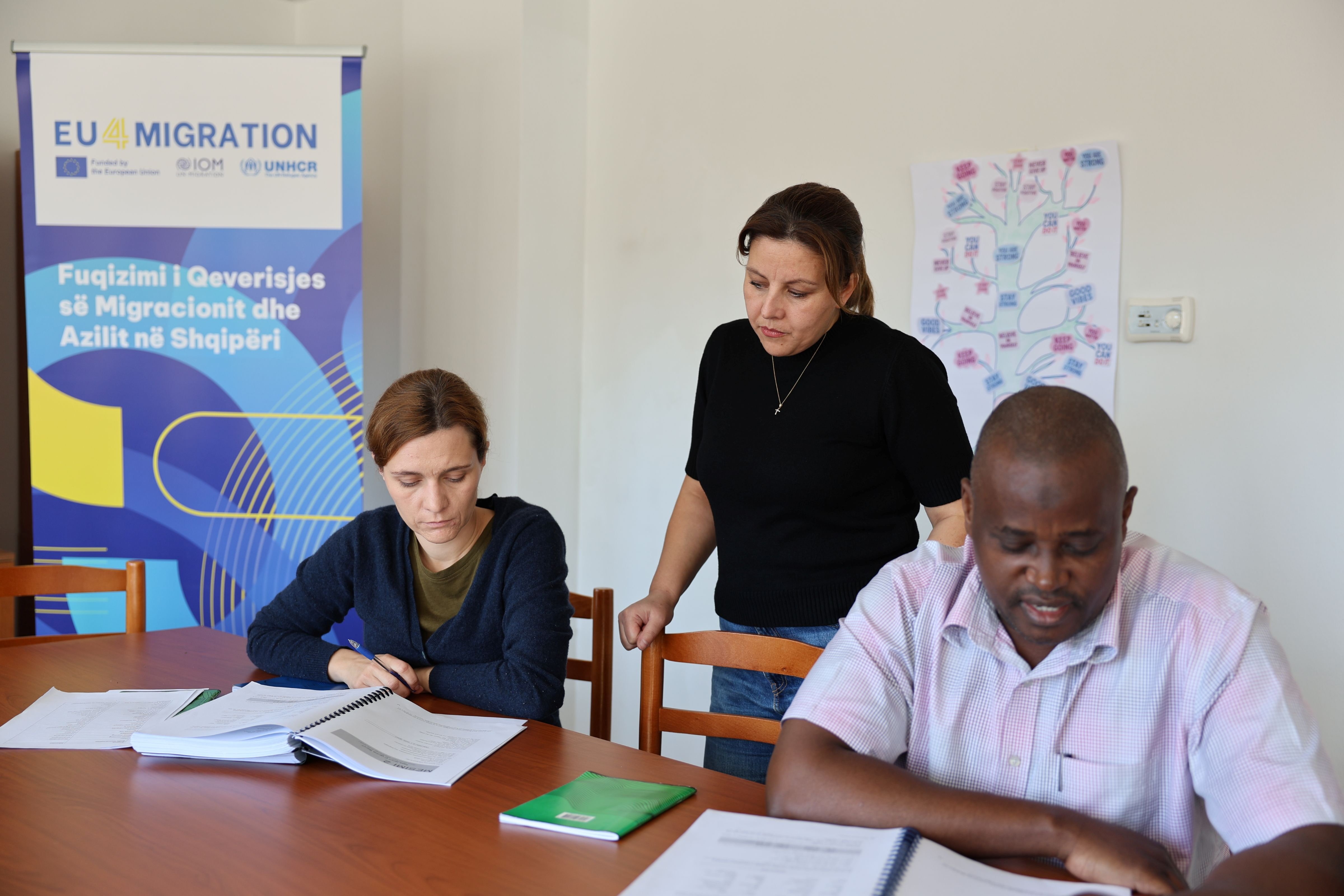 During a reading exercise, Jorida supports refugees Irma and Ibrahim as they practice pronunciation and comprehension. 