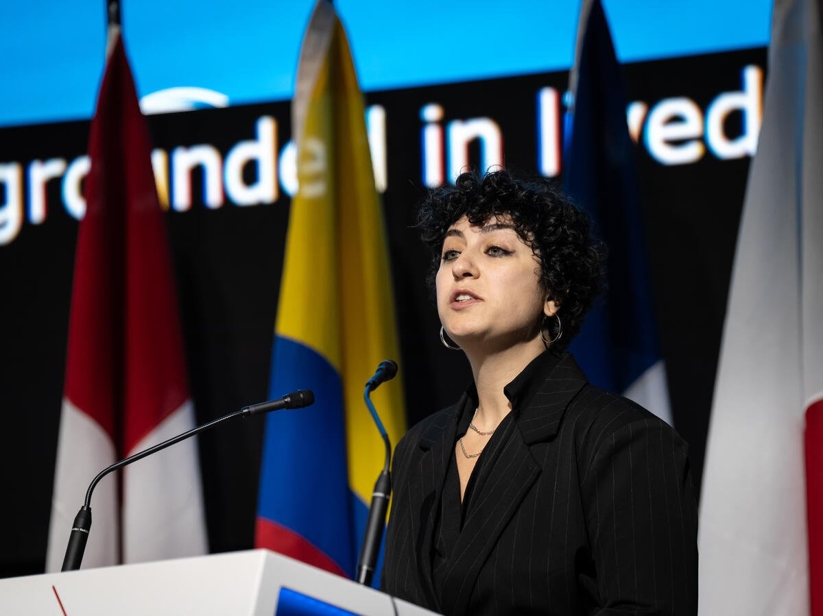A woman speaks into a microphone on stage.