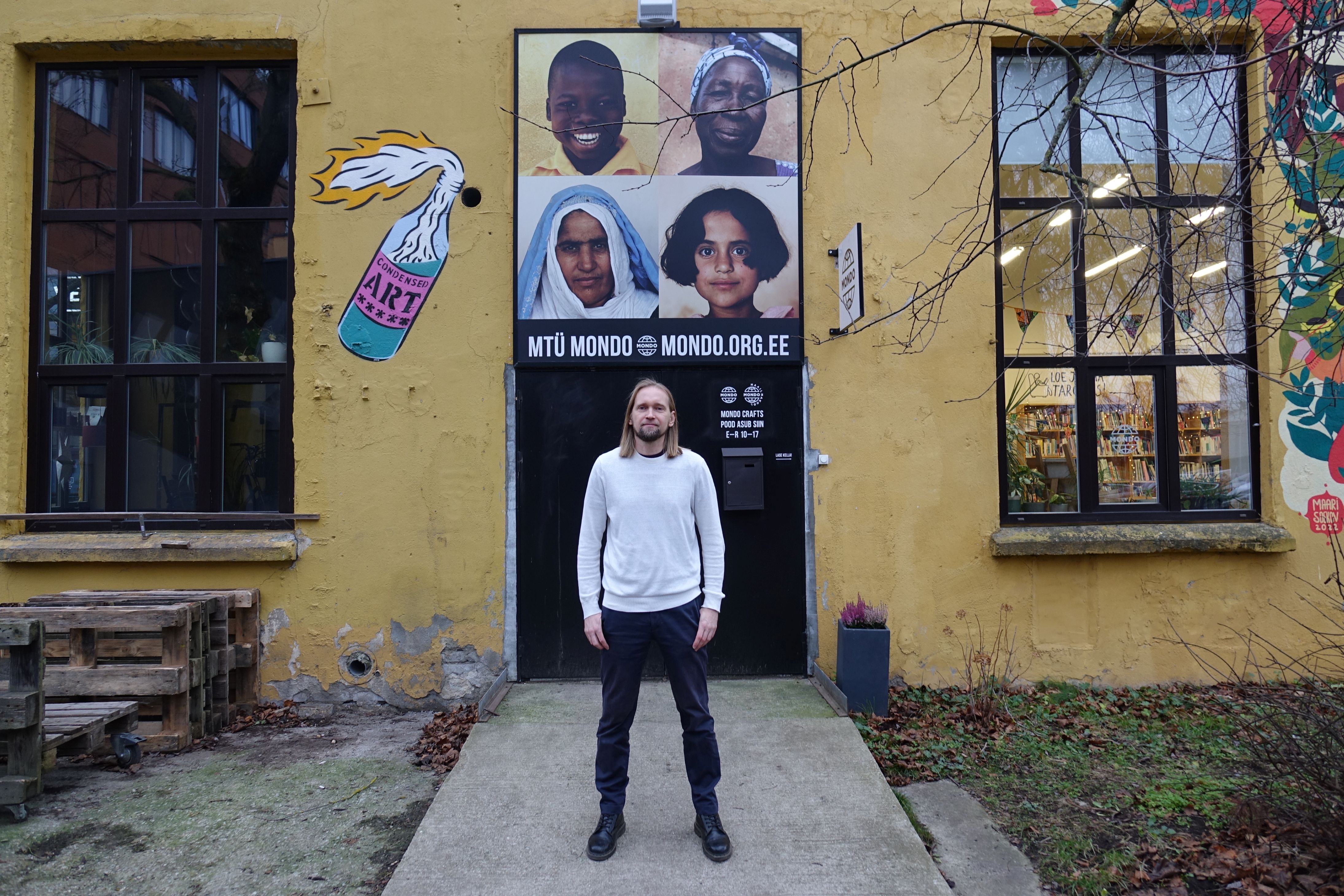 A man stands in front of building with different artwork
