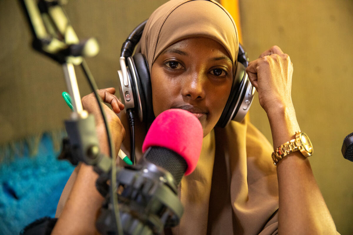 A woman wearing headphones talks into a microphone.