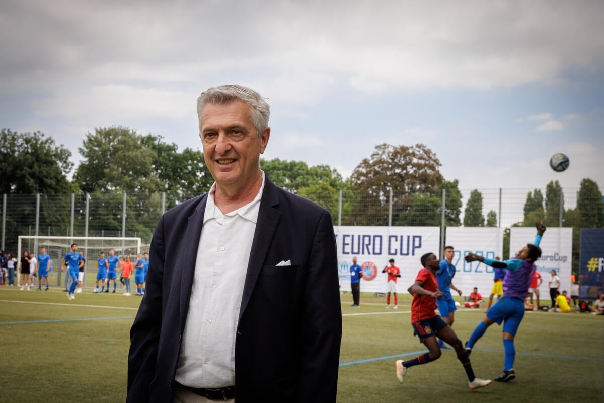 UN High Commissioner for Refugees Filippo Grandi stands on a football field