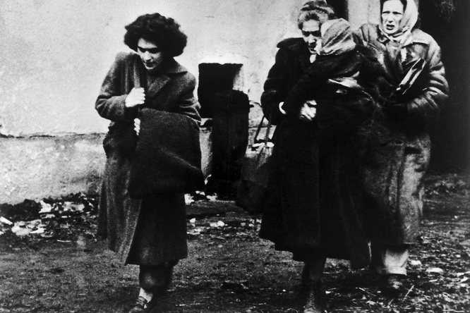 Black and white photo of three women and a child arriving at a refugee camp in Austria.