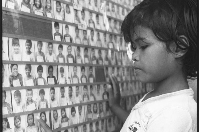A Cambodian refugee child looks at photos of other refugees