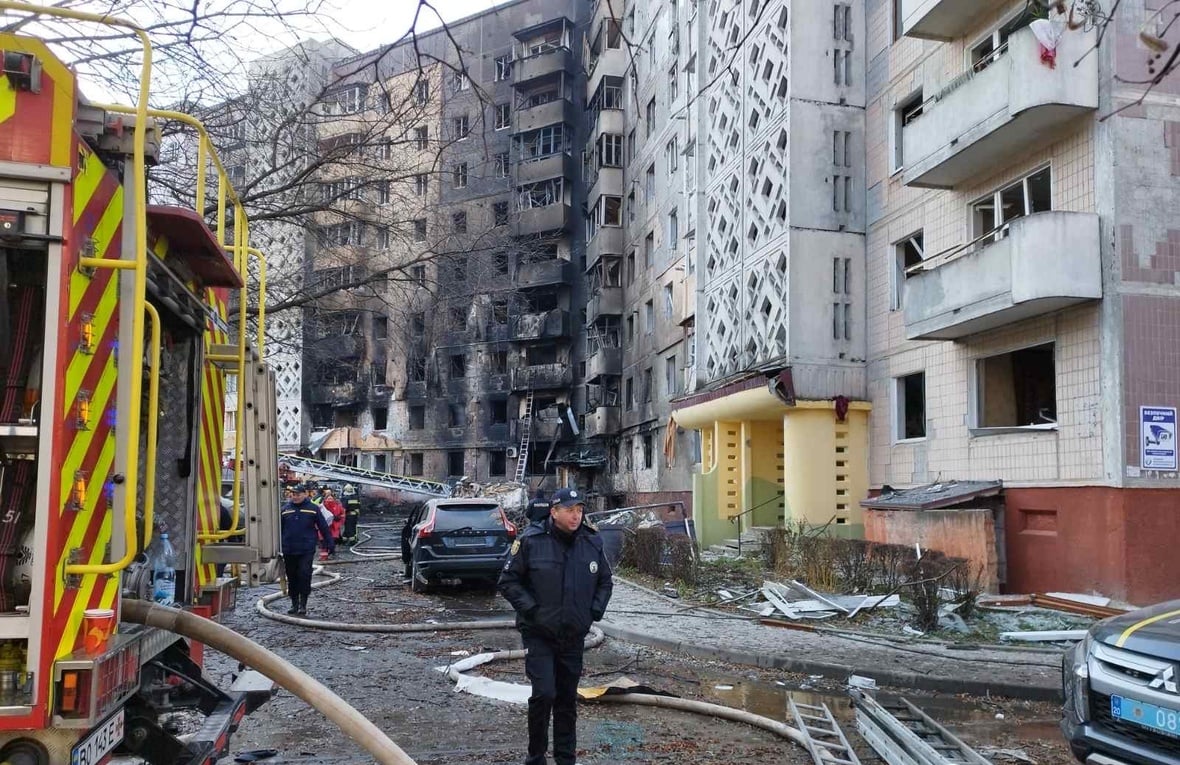 Emergency service vehicles and staff in the street in front of fire and bomb damaged buildings
