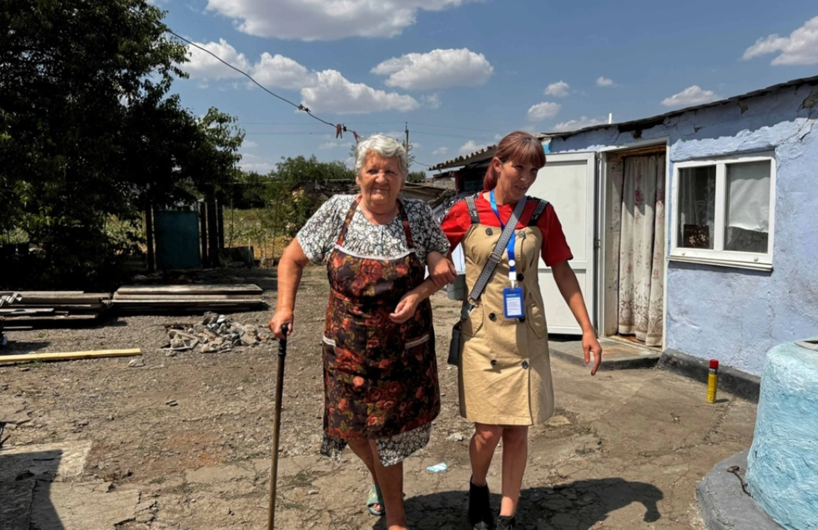 Older Ukrainian woman walking with the social facilitator