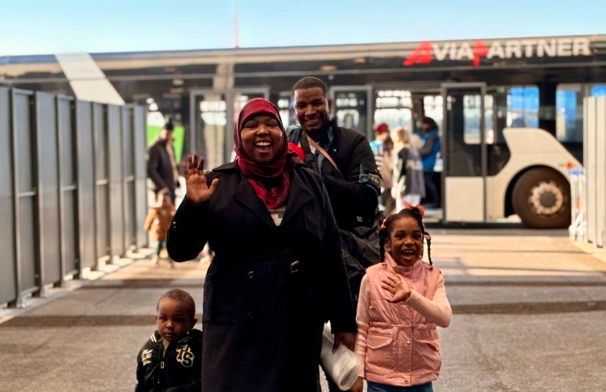 A smiling family in front of an airport shuttle bus