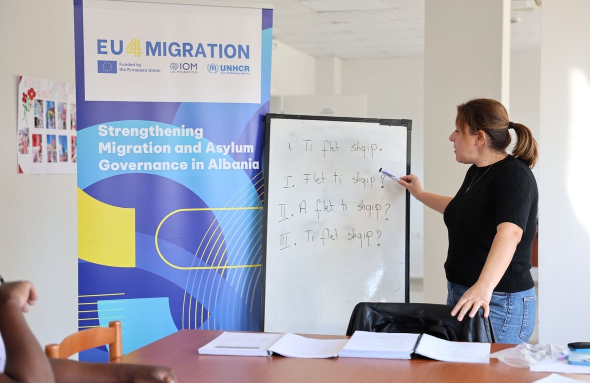  Jorida Pina, a seasoned Albanian language teacher, stands in a classroom at the National Reception Centre for Asylum in Tirana, teaching a lesson on commonly used Albanian verbs. 